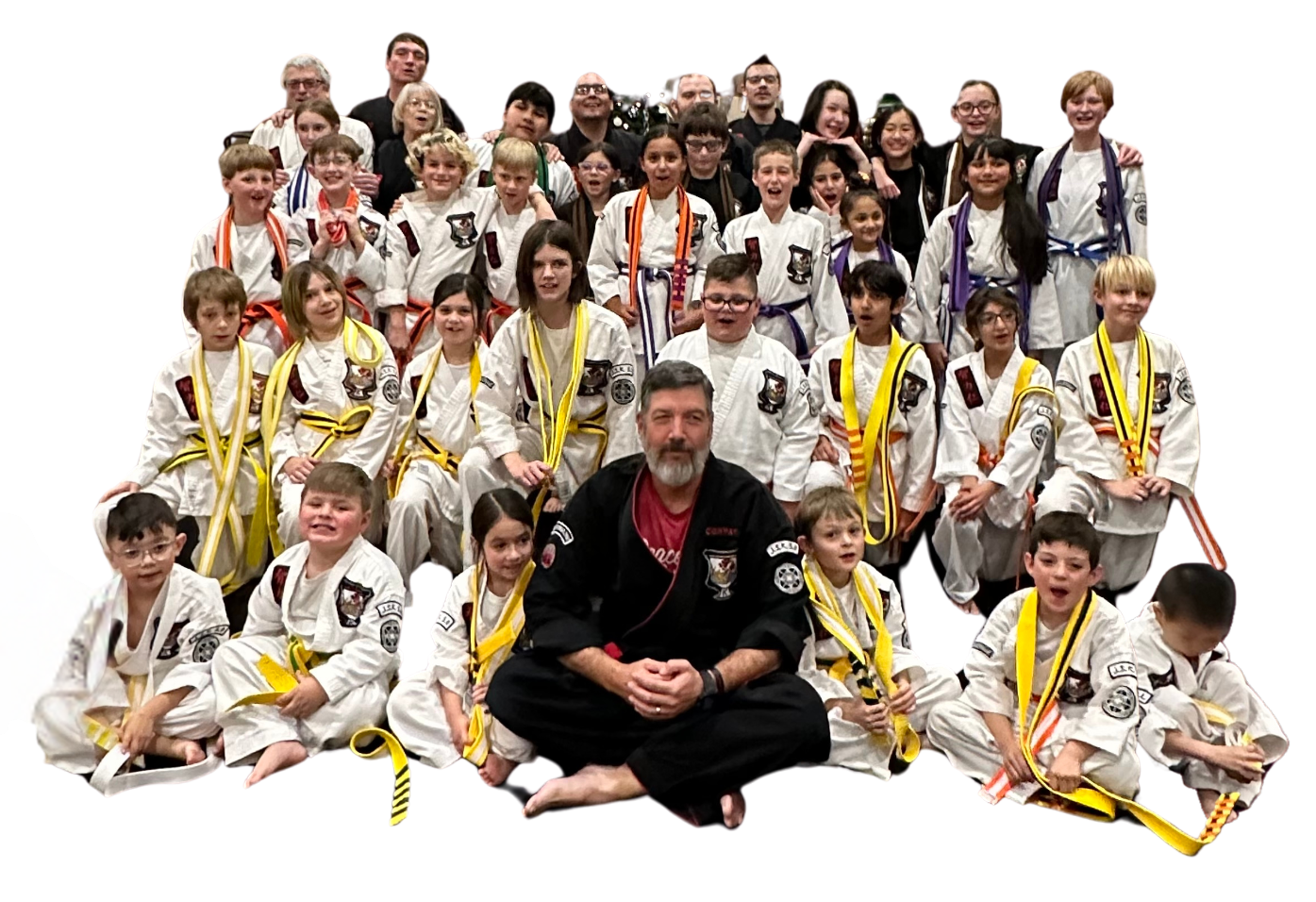 A group of kids in karate uniforms are sitting on the floor drinking water