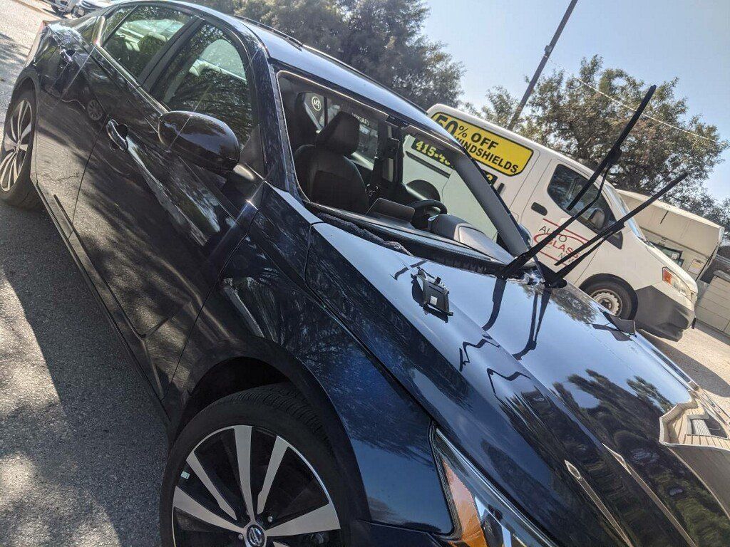 A blue car is parked on the side of the road next to a yellow van.