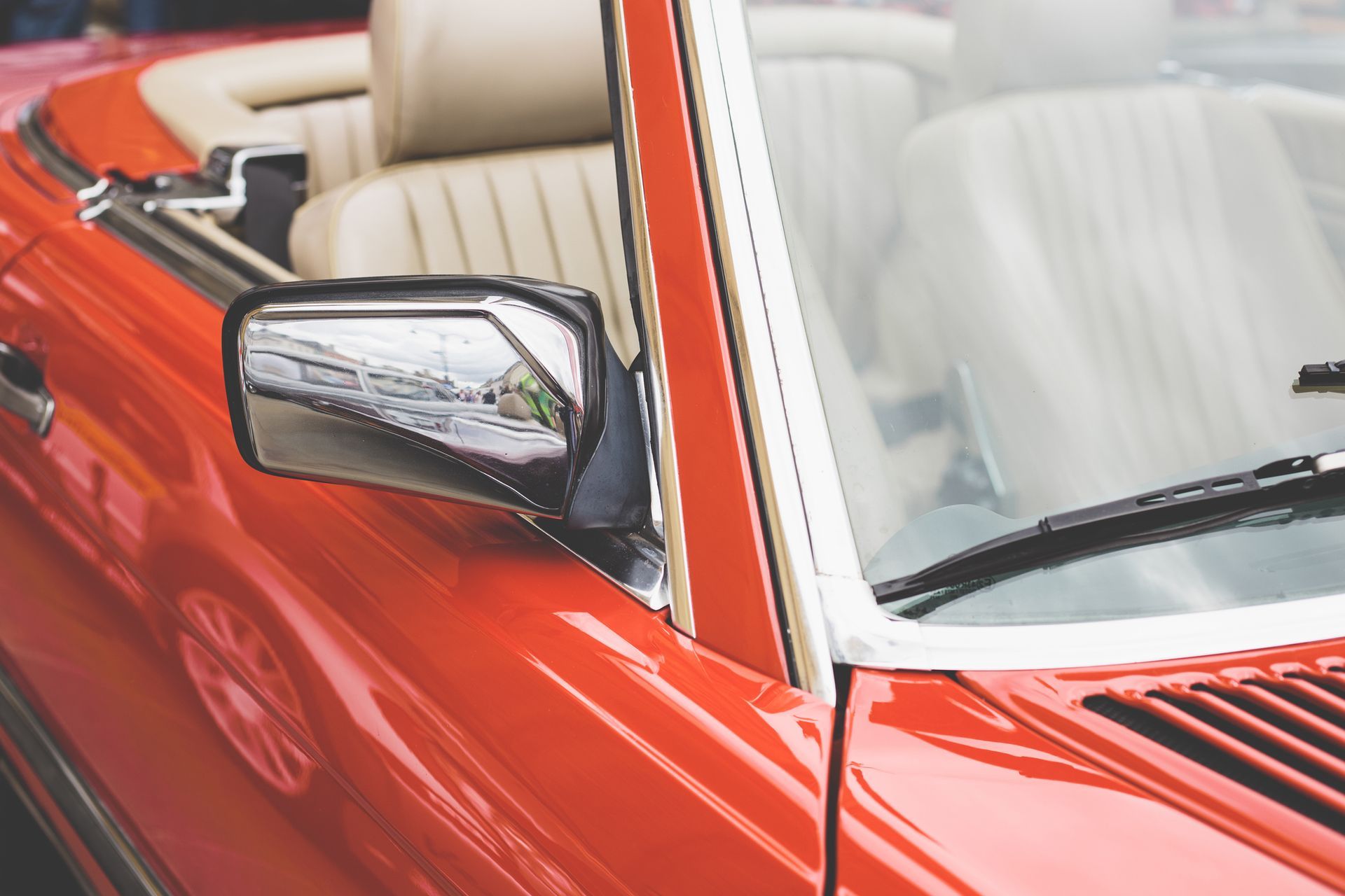 A yellow car with a reflection of a building in the windshield