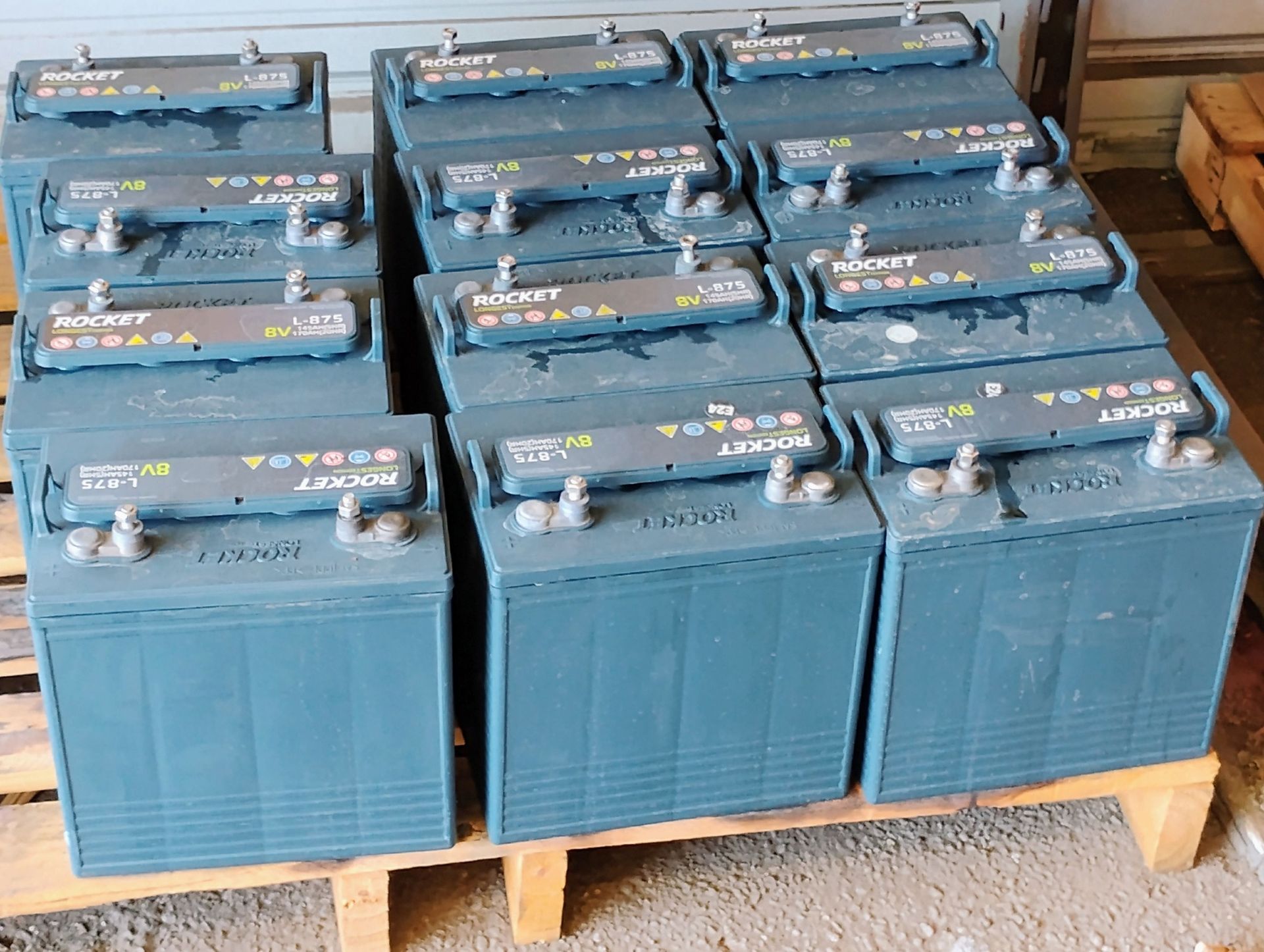 A bunch of batteries are stacked on top of each other on a wooden pallet.