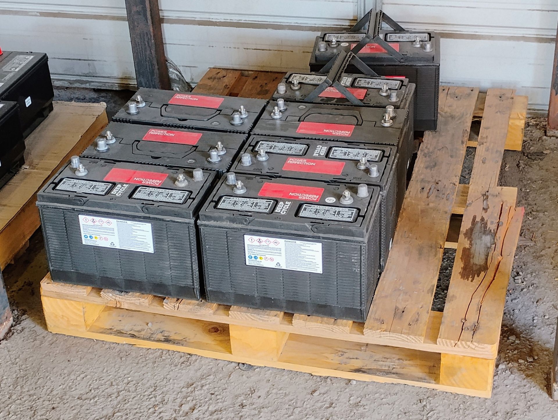 A bunch of batteries are sitting on a wooden pallet.