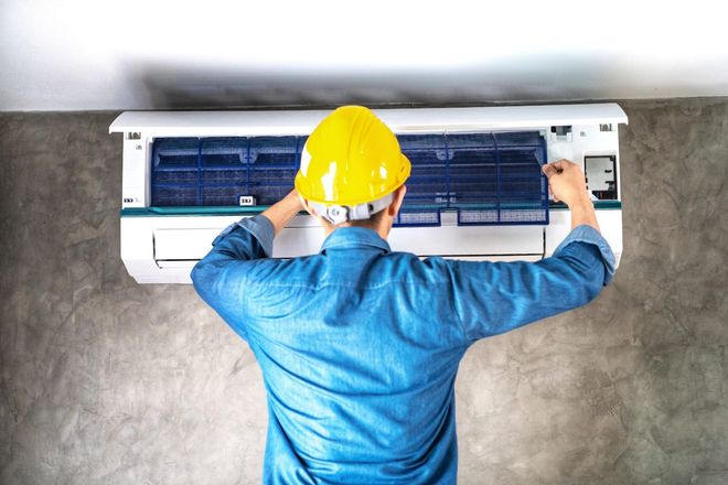 Technician man repairing ,cleaning and maintenance Air conditioner on the wall in bedroom