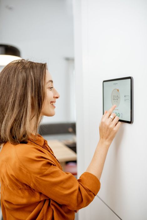 Young woman controlling temperature in the living room with digital touch screen panel