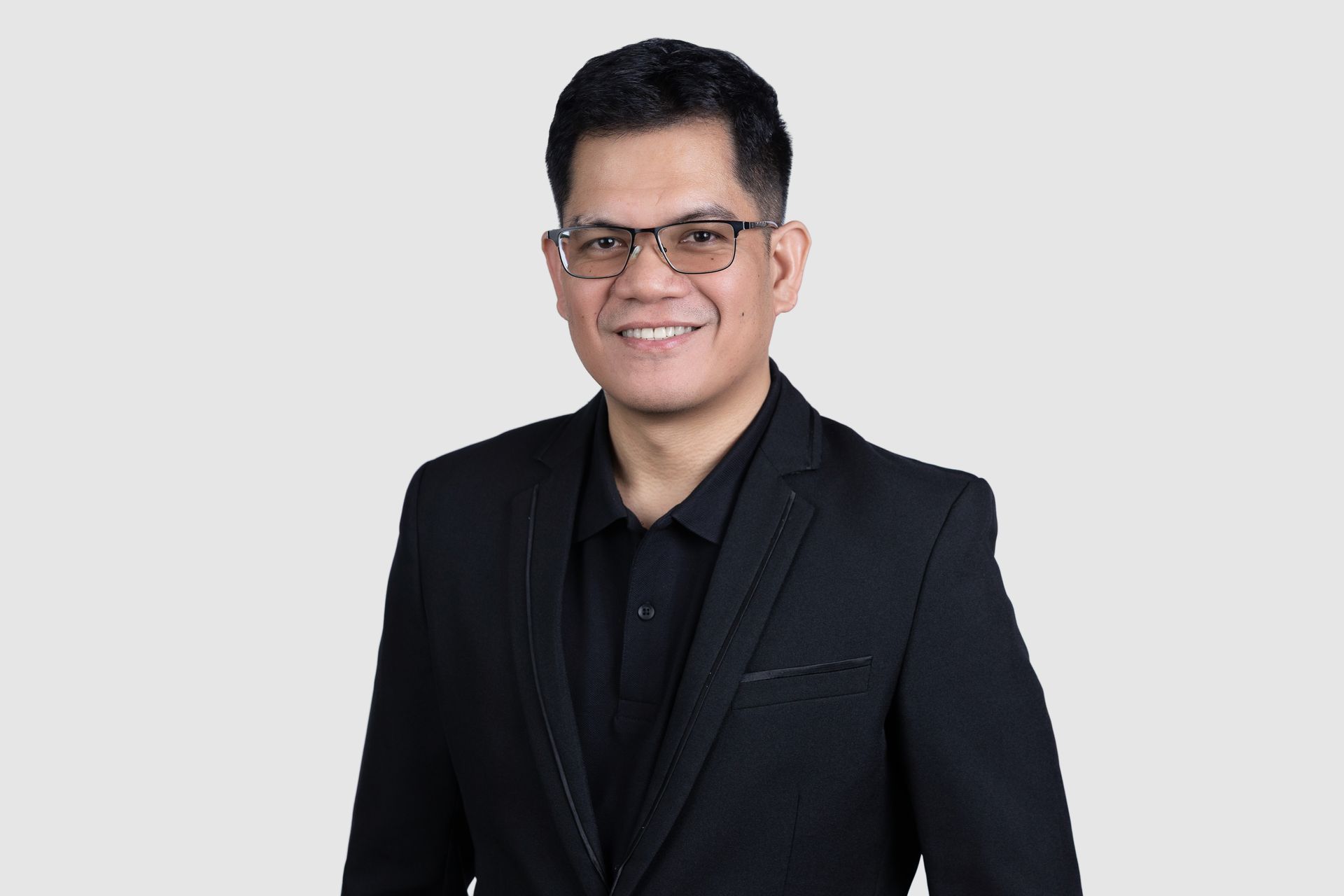 A woman is sitting at a table in front of a window and smiling