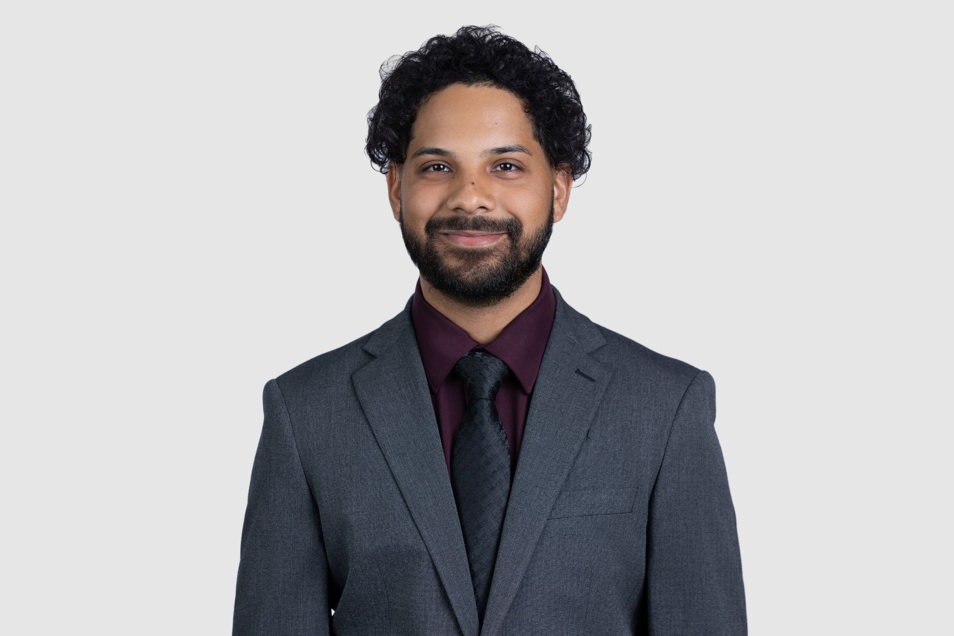 A man with a beard wearing a black shirt and red tie