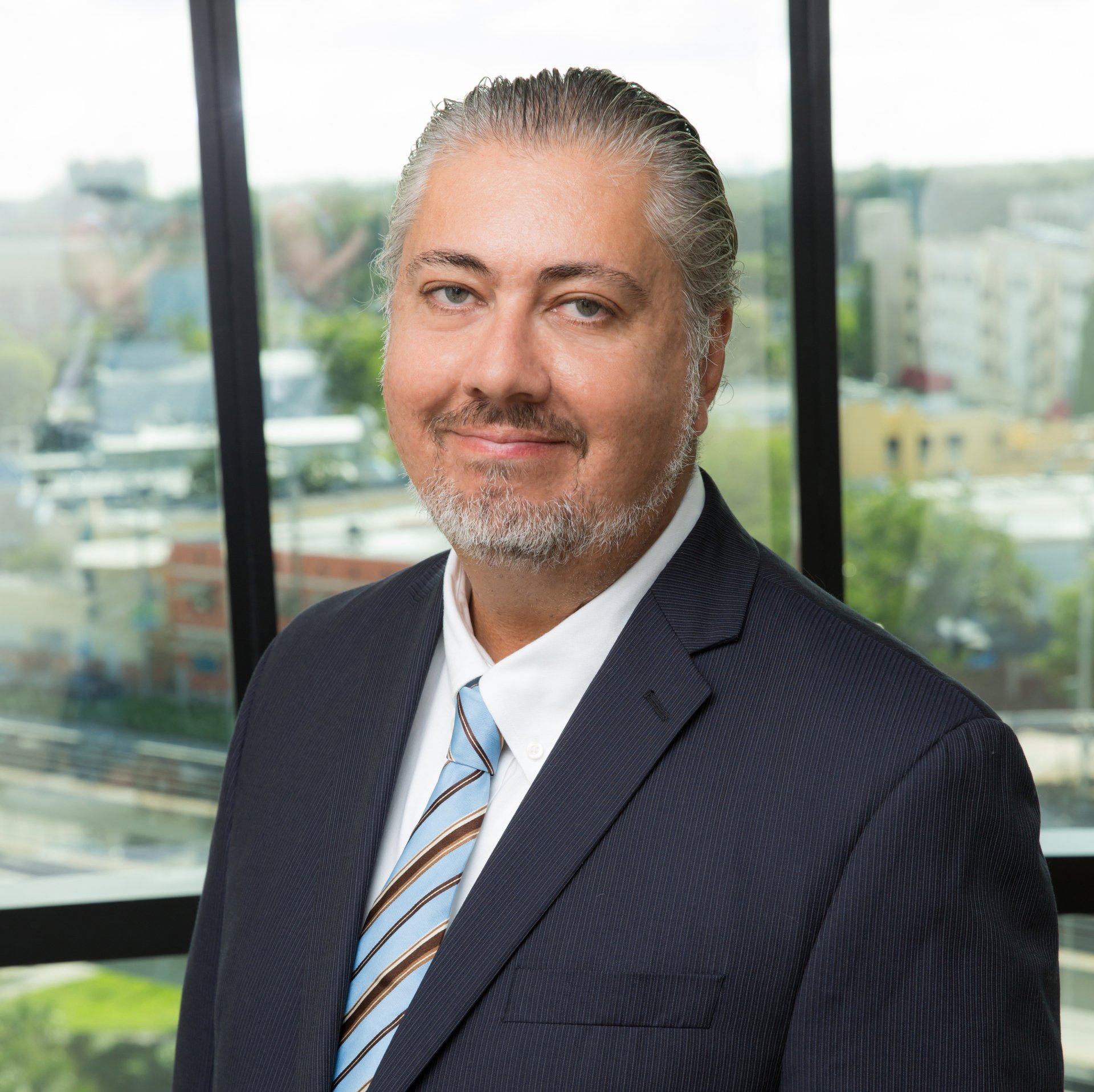 A man in a suit and tie is standing in front of a window.