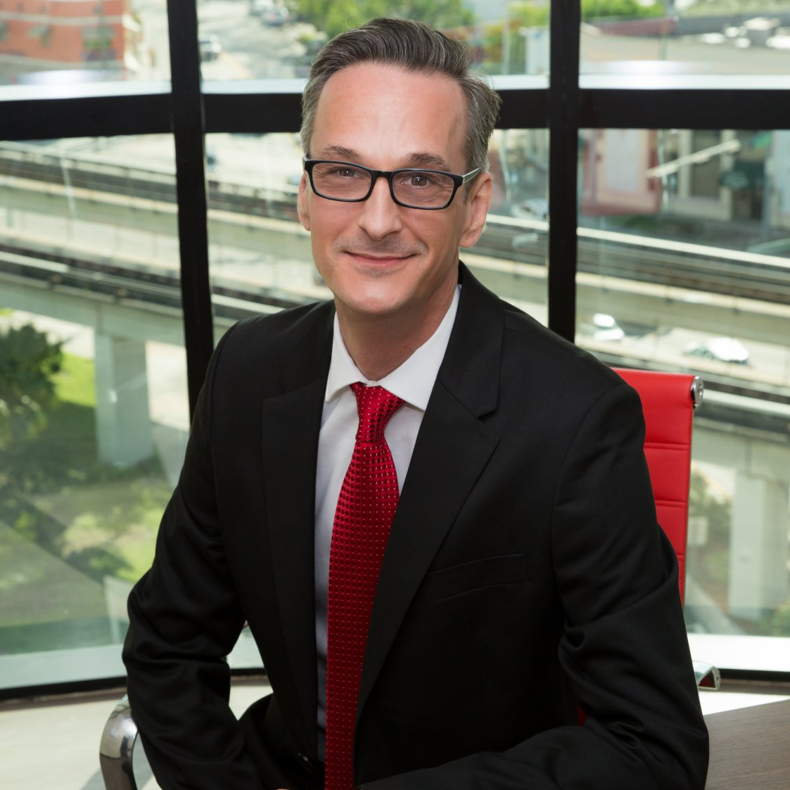 A man in a suit and tie is sitting in front of a window