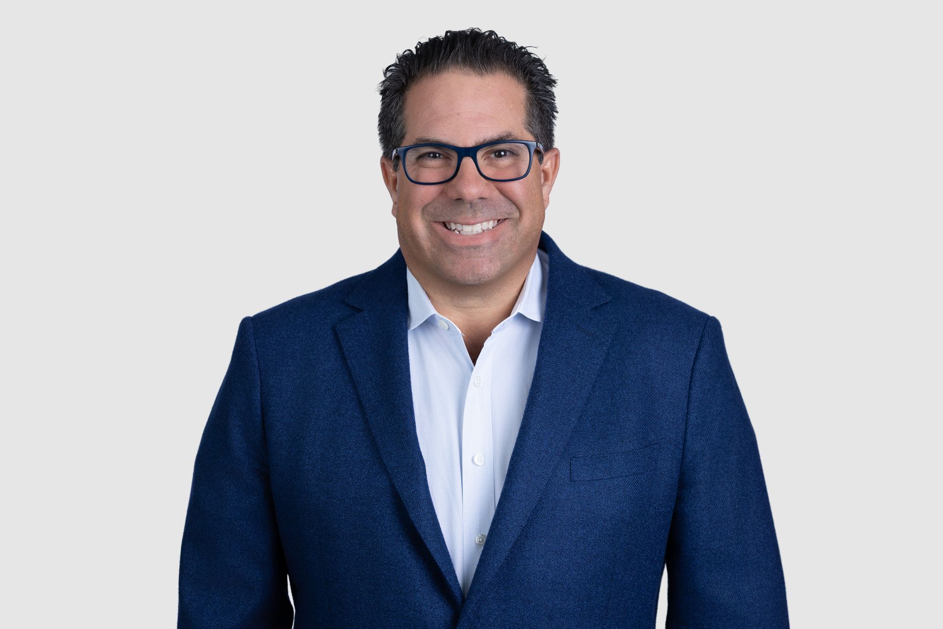 A man in a suit and tie is sitting in front of a window.