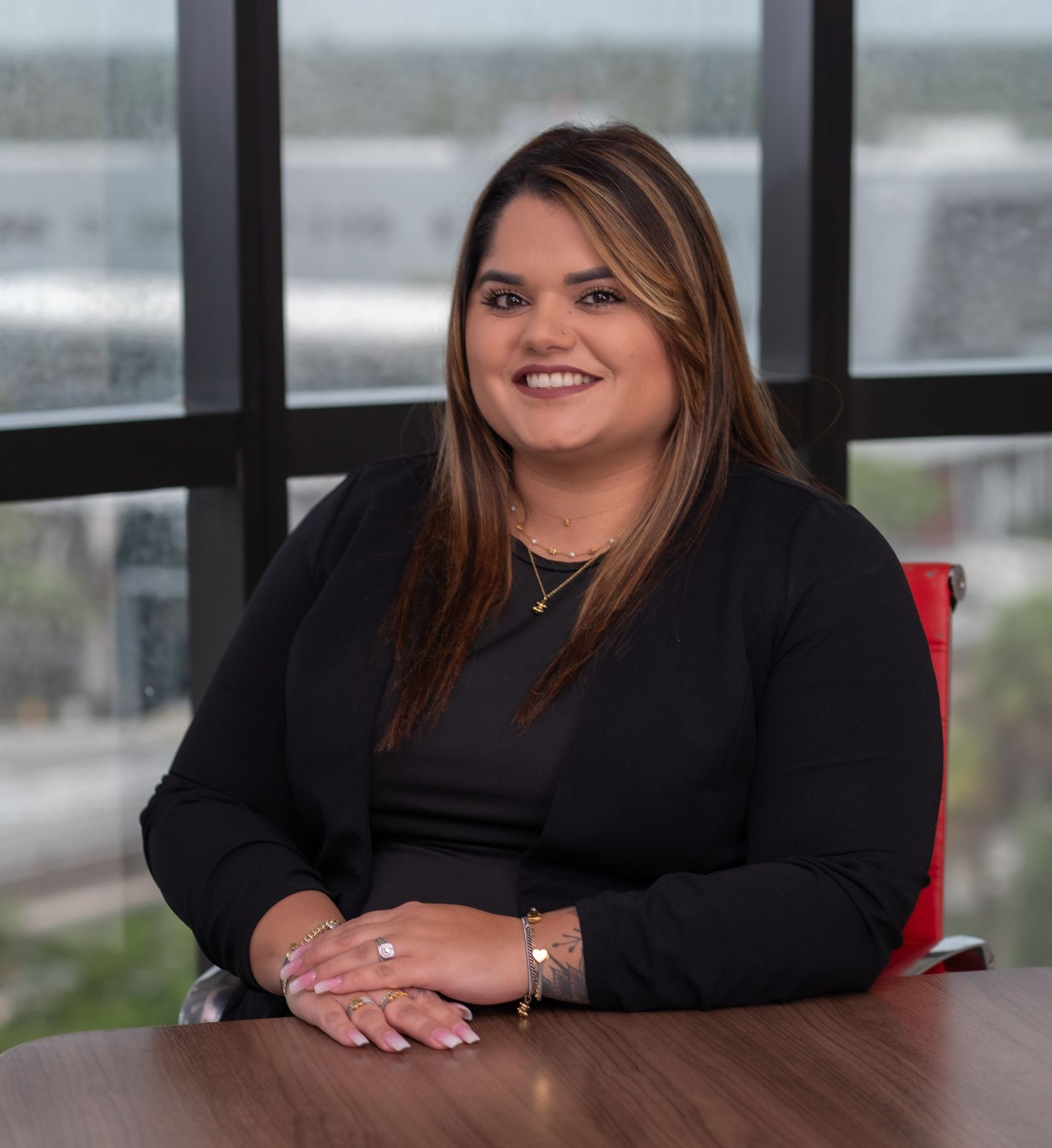 A woman is sitting at a desk in front of a window.