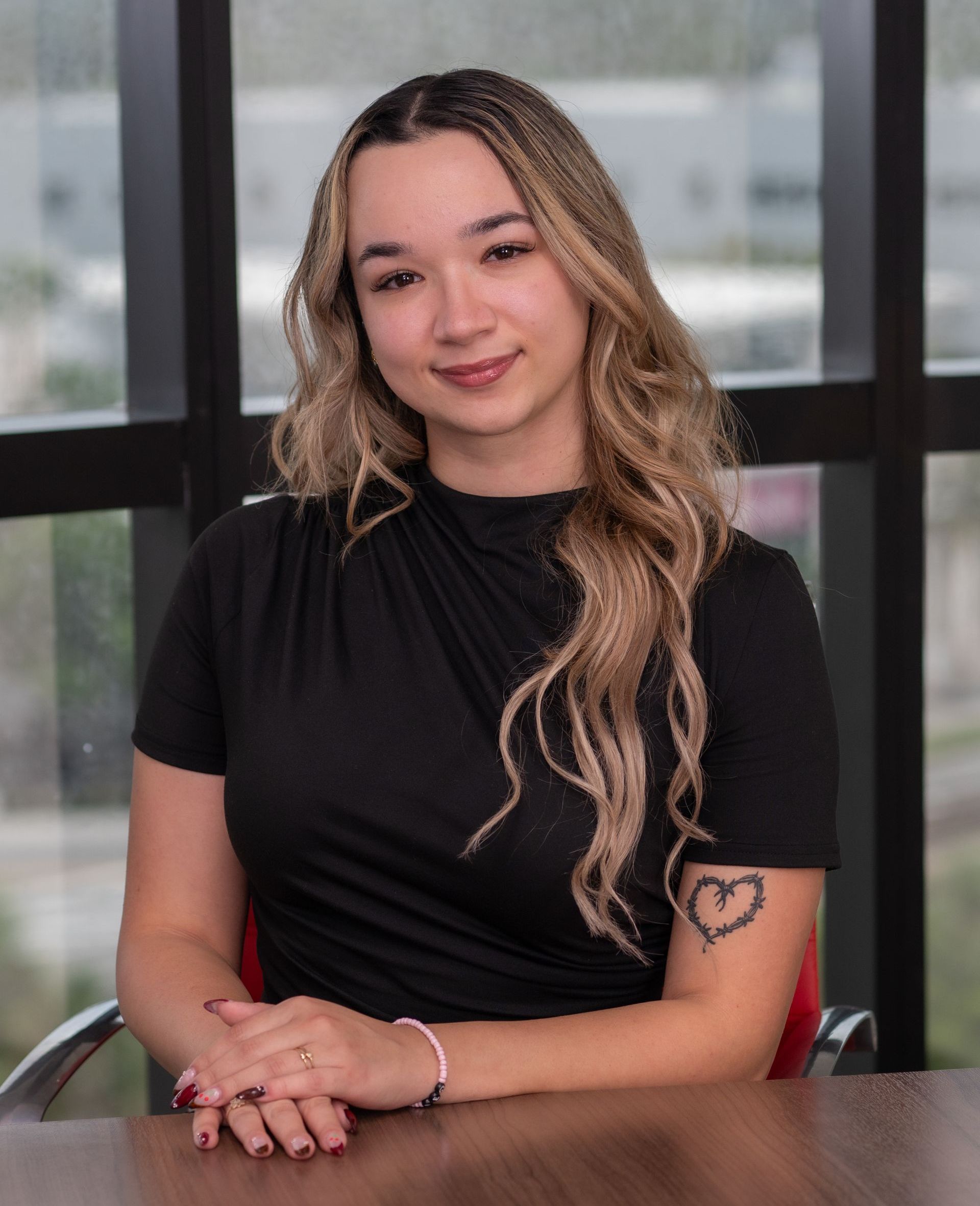 A woman wearing a black polka dot shirt is smiling for the camera