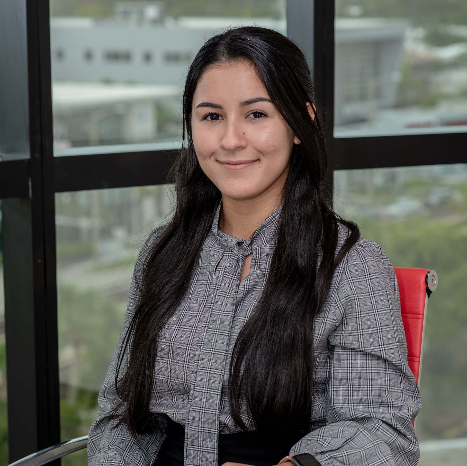 A man in a suit and tie is sitting in front of a window.