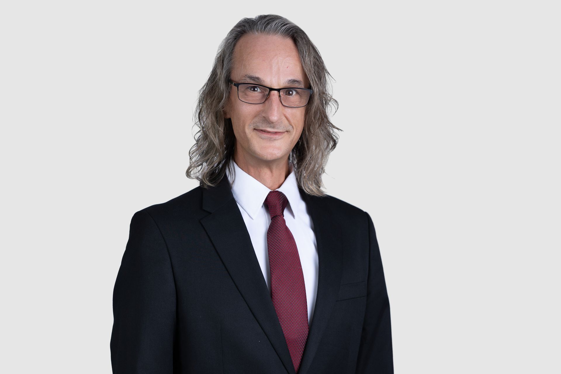 A man in a suit and tie is sitting in front of a window