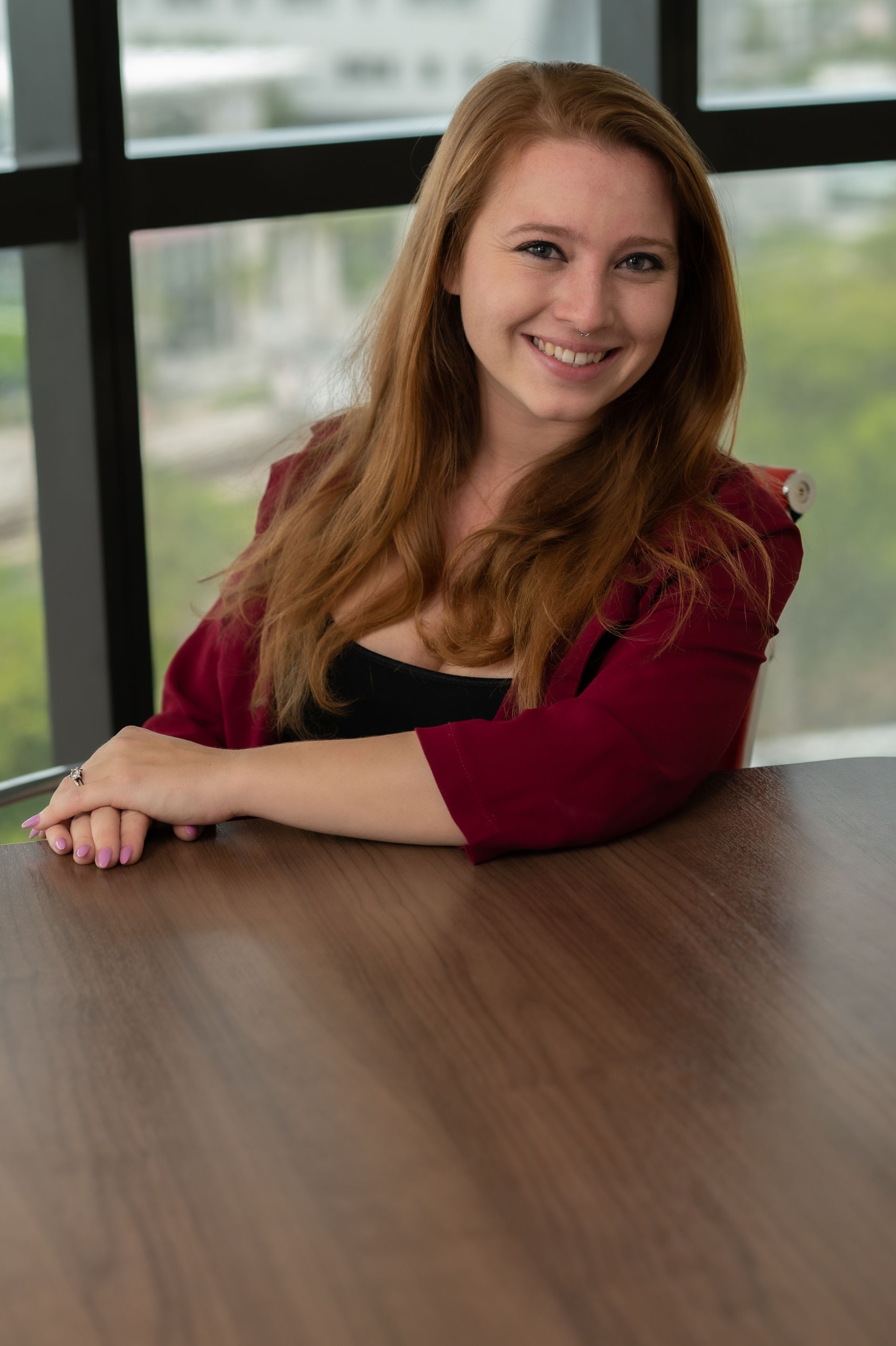 A woman is sitting at a table in front of a window.