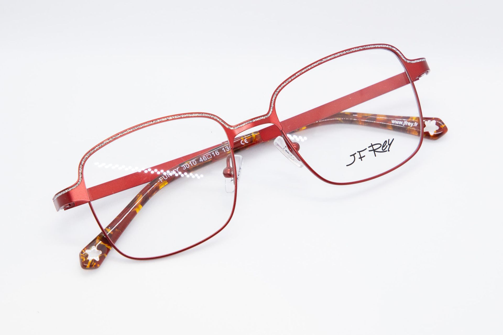 Une paire de lunettes rouges sur une surface blanche.