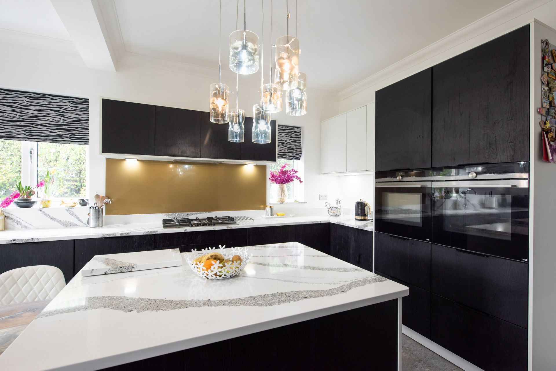 An interior view of a modern kitchen, painted white with black cabinets and a quartz countertop.