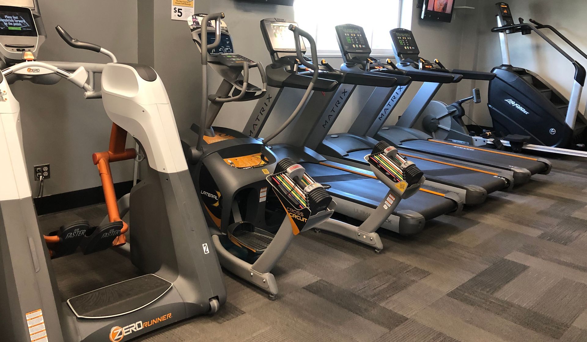 A row of treadmills are lined up in a gym.