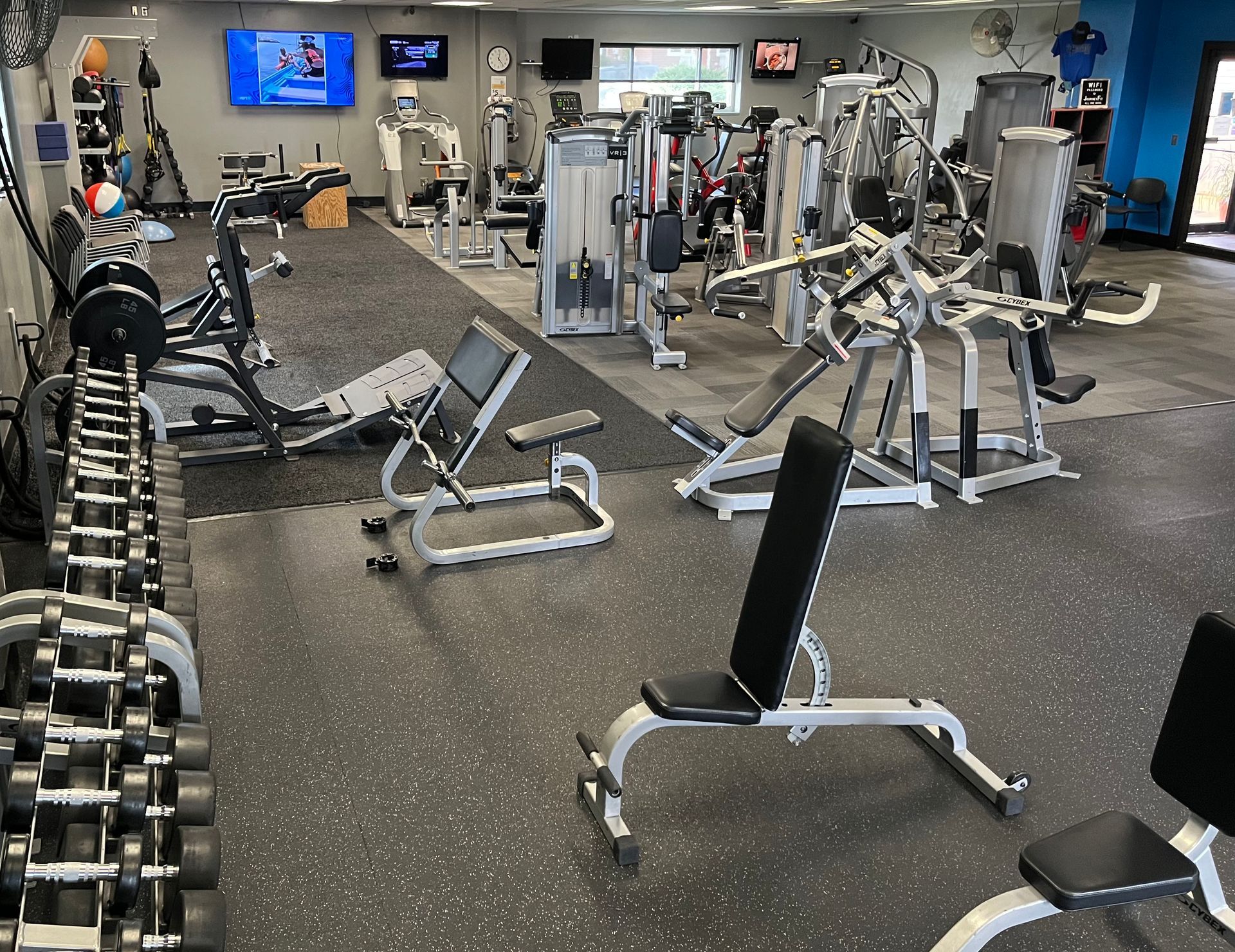 A gym filled with lots of exercise equipment and dumbbells.