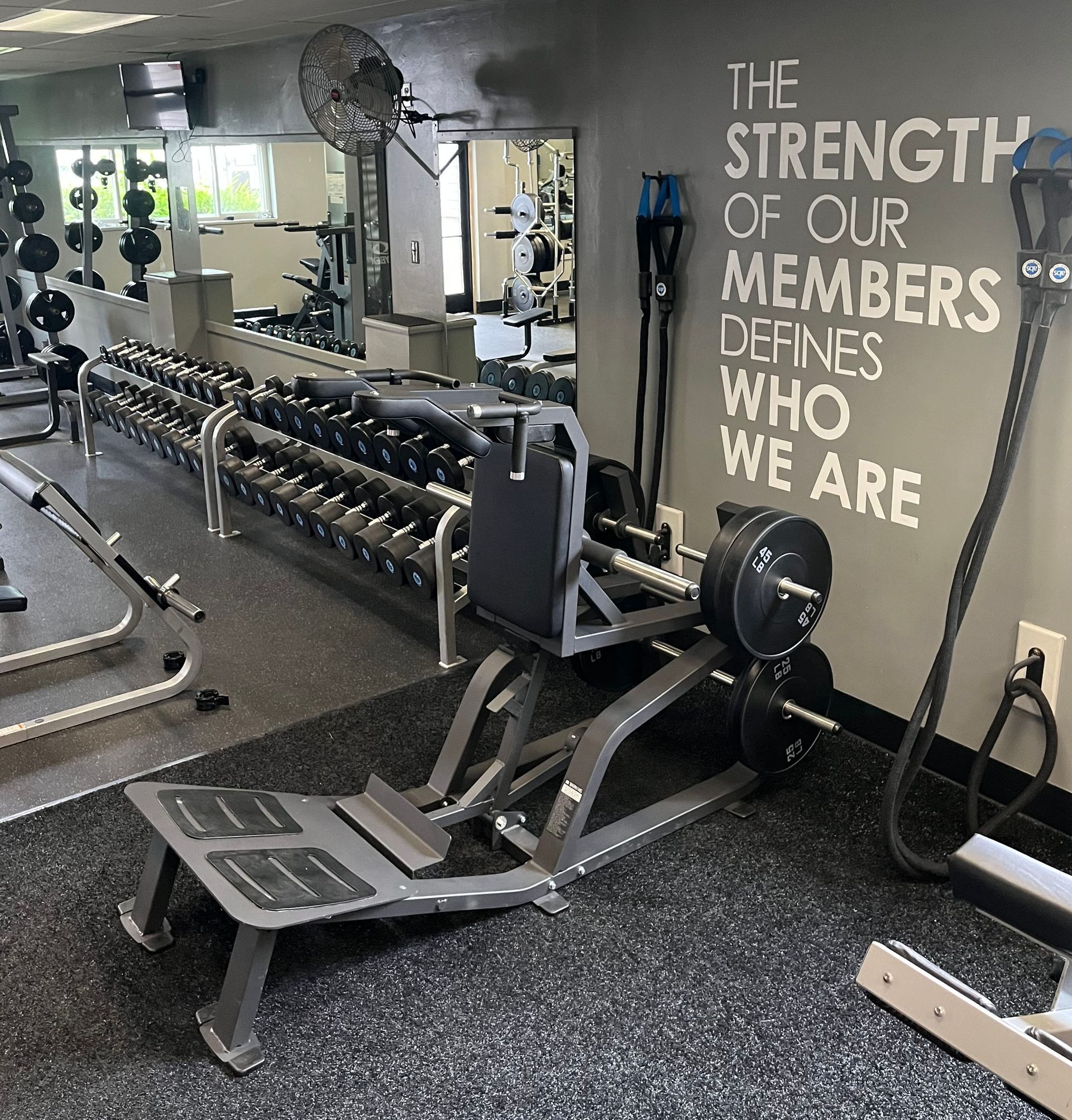 A gym with a sign that says the strength of our members defines who we are