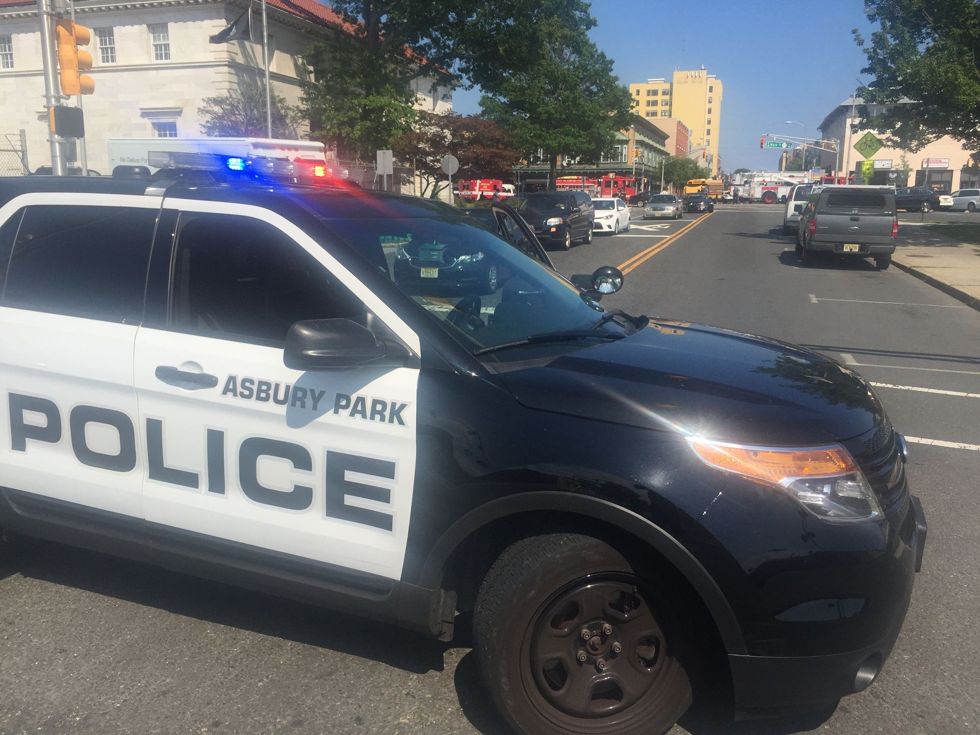 Asbury Park Police car with flashing lights, parked on a street with other vehicles.