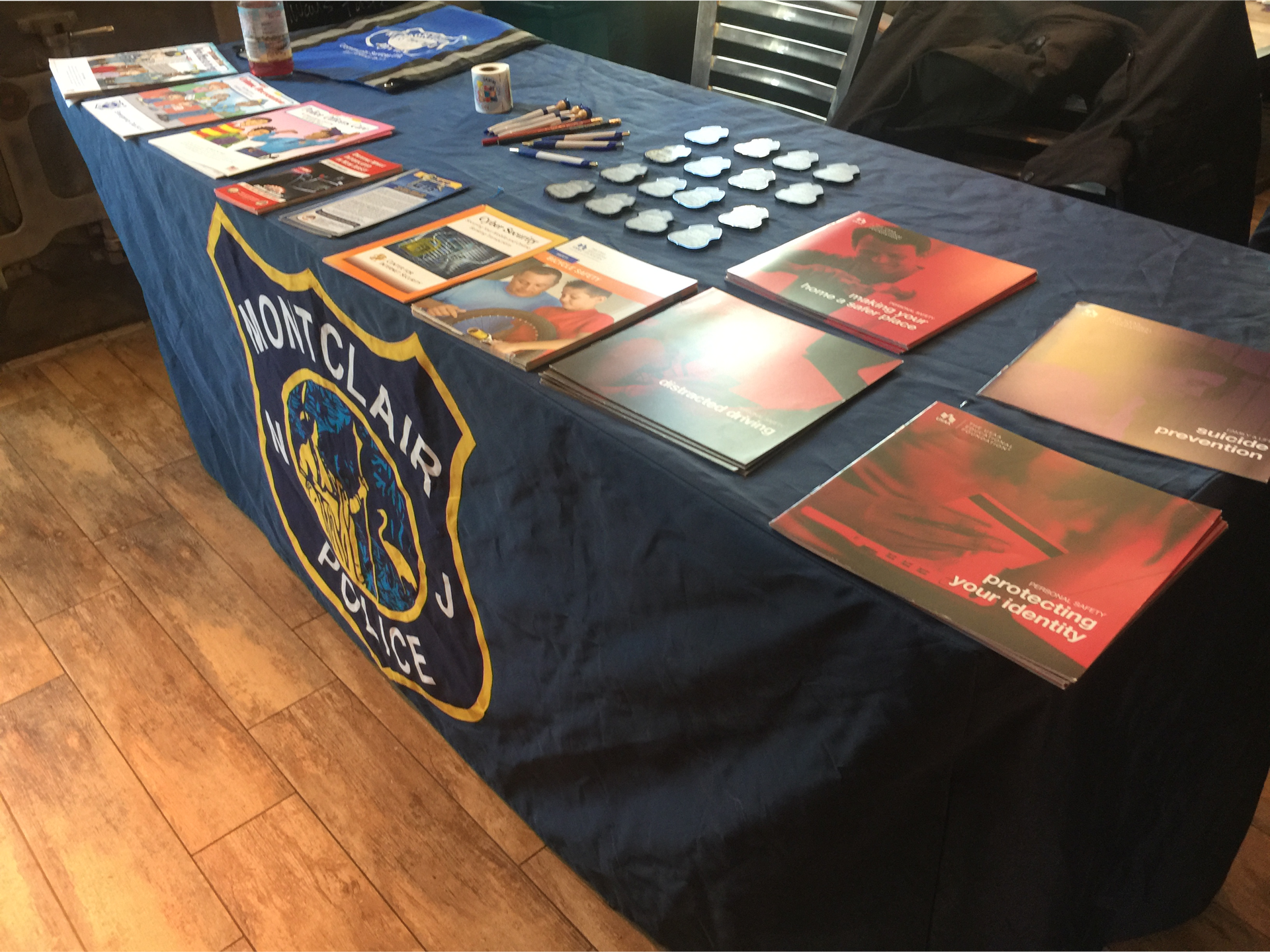 A table covered with a navy blue Montclair Police banner displays brochures and promotional materials.