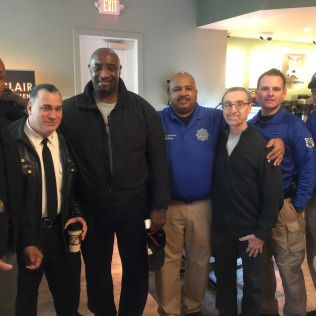 A group of people, some in uniform, posing indoors near an exit.