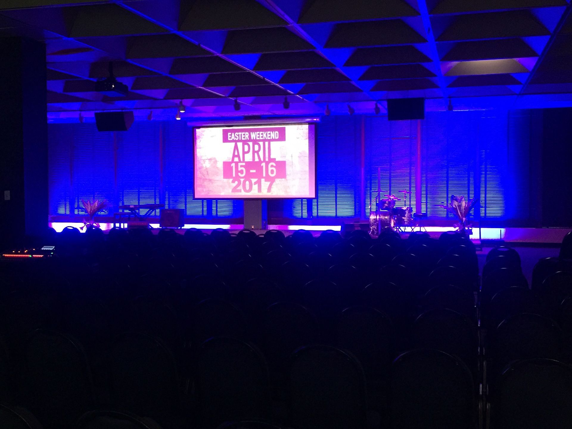 A stage lit in blue, with a screen displaying 