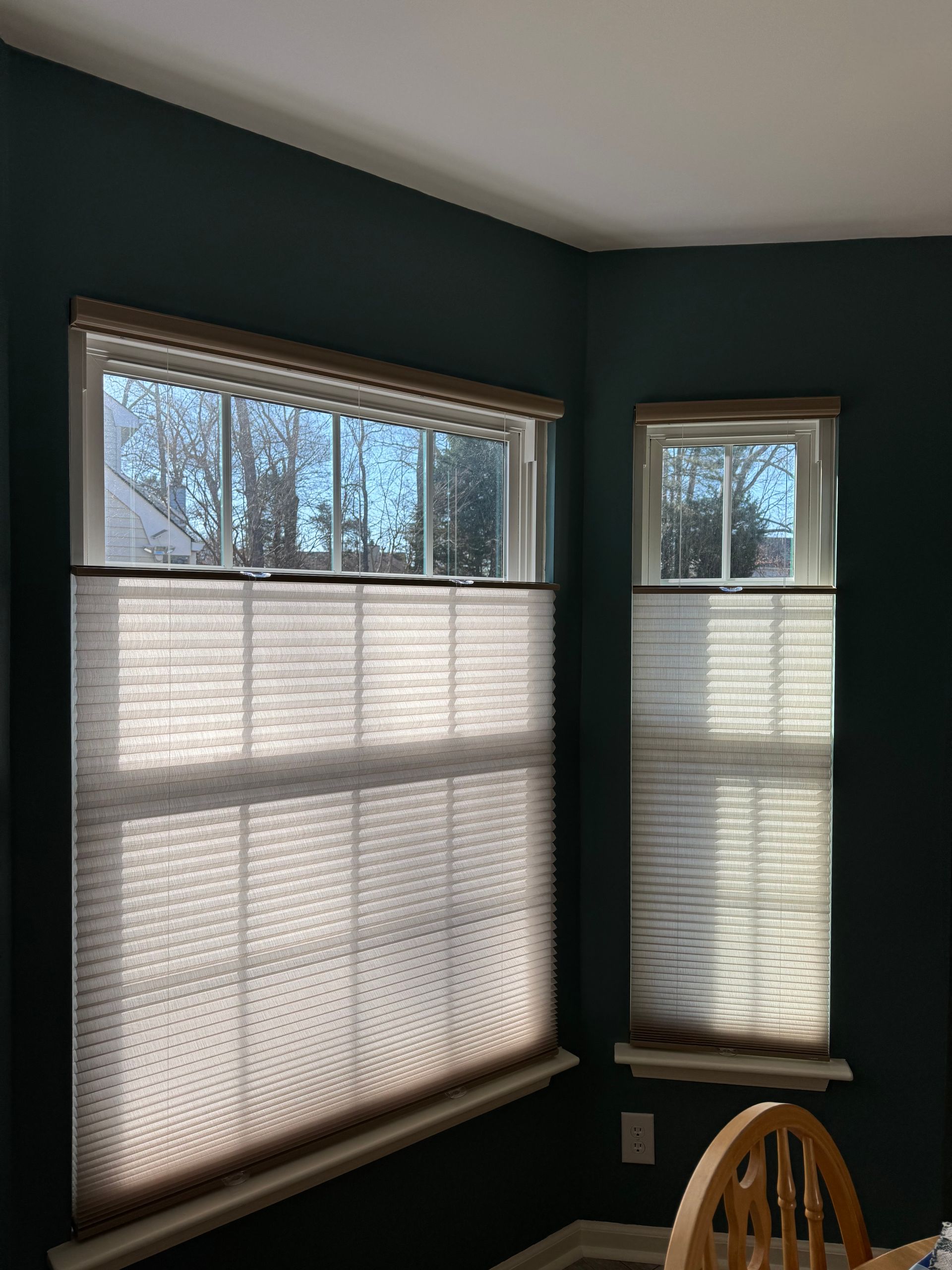 A dining room with a table and chairs and two windows with blinds.