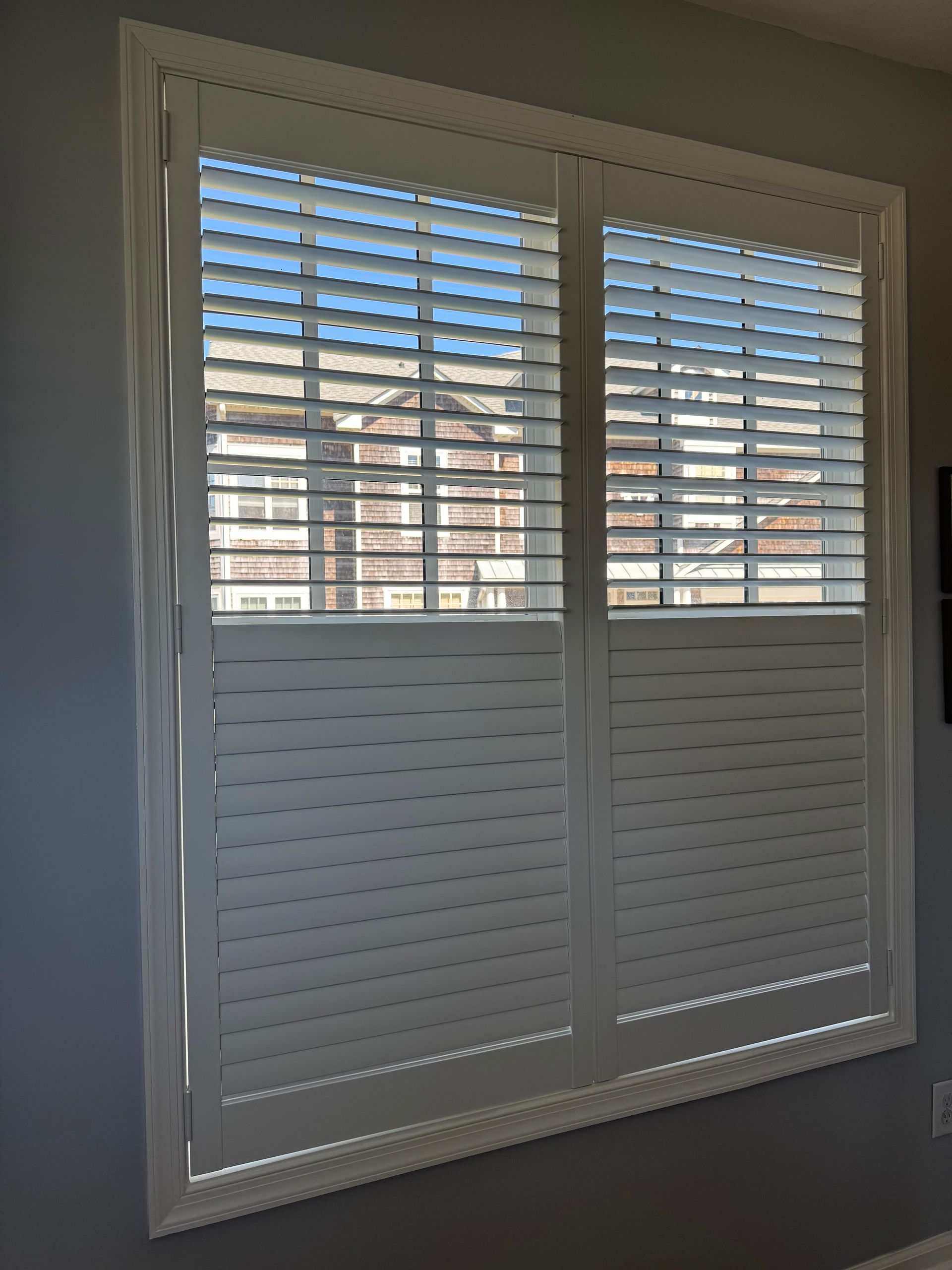 A pair of white shutters on a window in a room