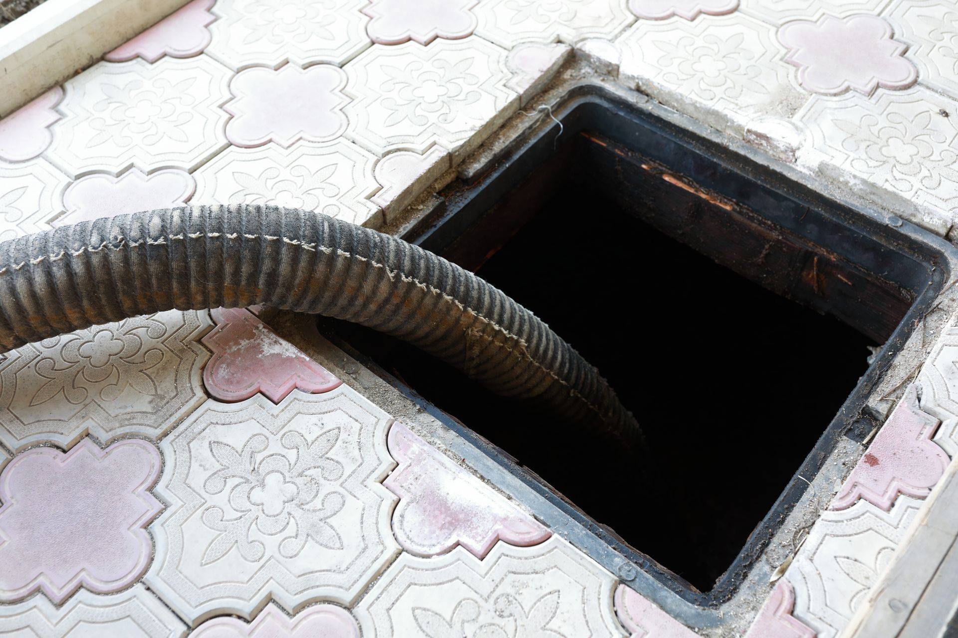 Drain cleaning hose inserted into a floor access opening during professional plumbing service.