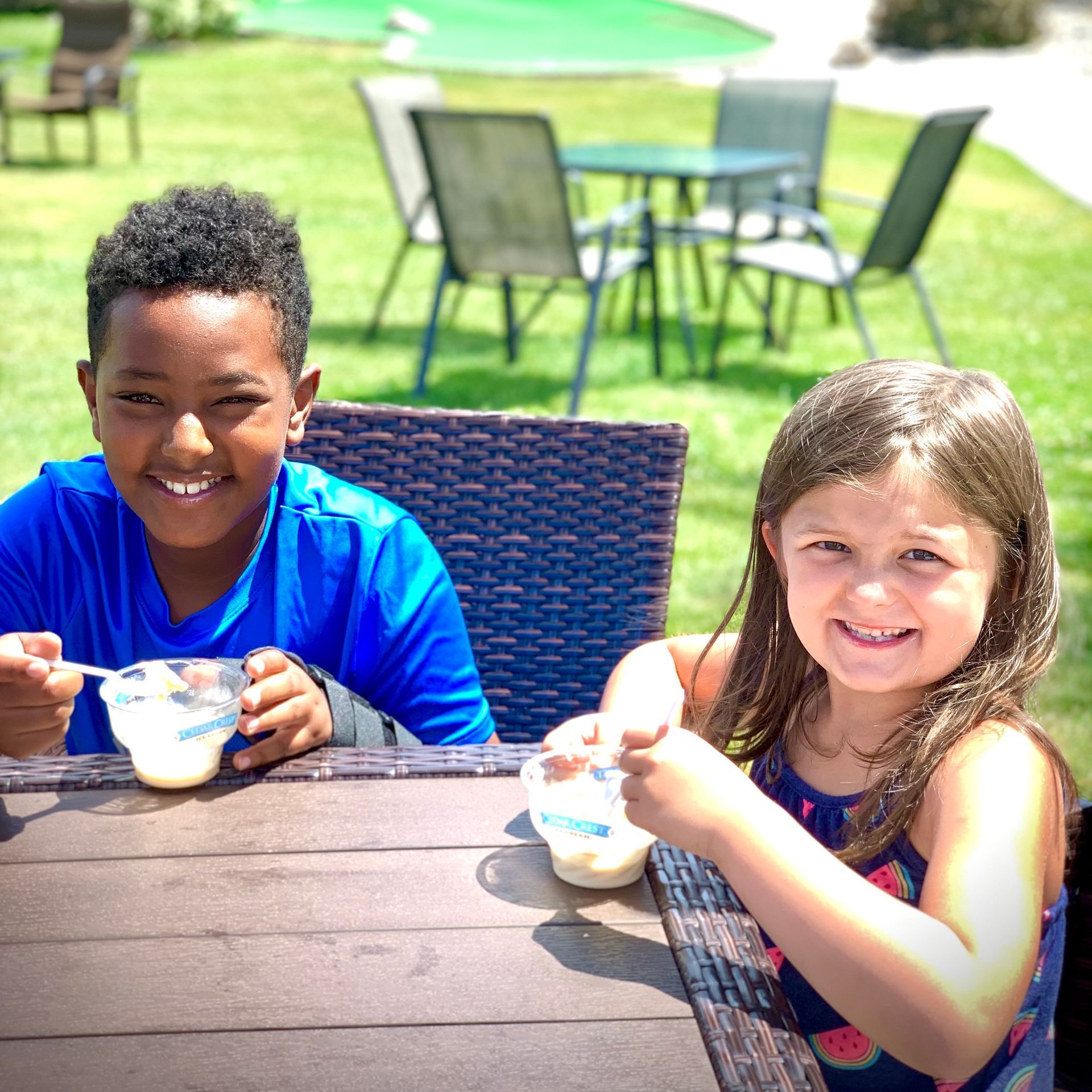 A boy and a girl are sitting at a table eating ice cream