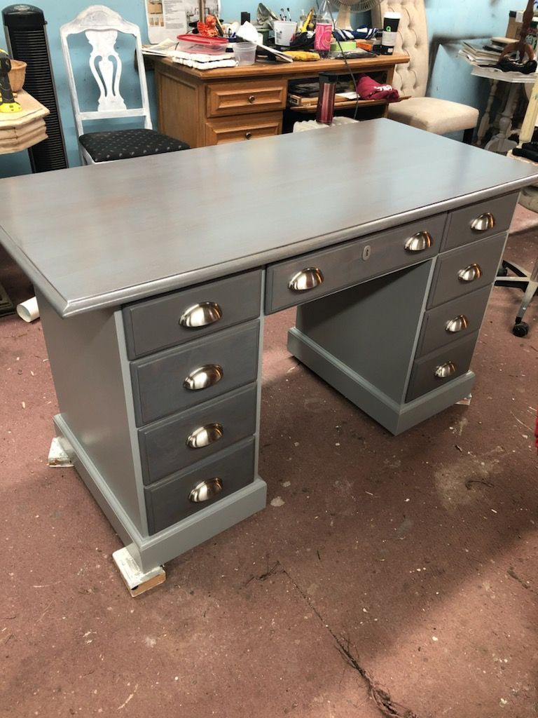 A gray desk with drawers and a chair in a room.