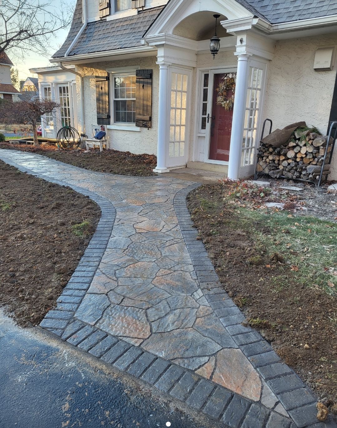 Stone path leading to a house's front door with a brick border.