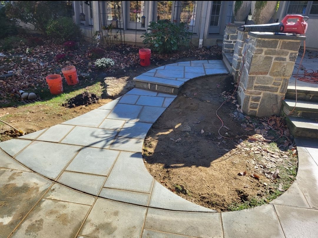 Stone pathway with steps leading to a building entrance; unfinished landscaping.