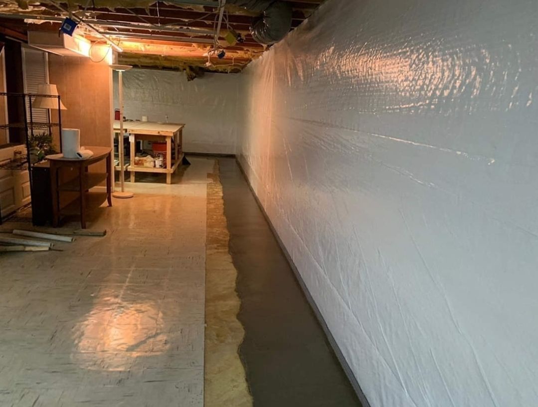 Basement with white coated walls and a gray concrete strip along the wall's base.