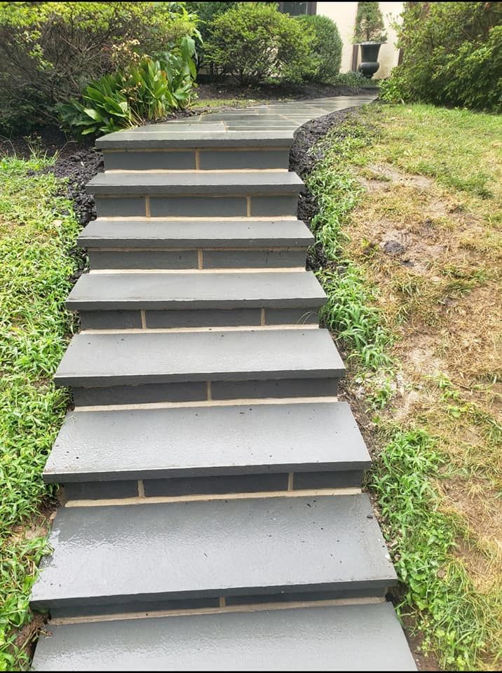 Stone steps leading uphill through greenery, with a paved walkway continuing.