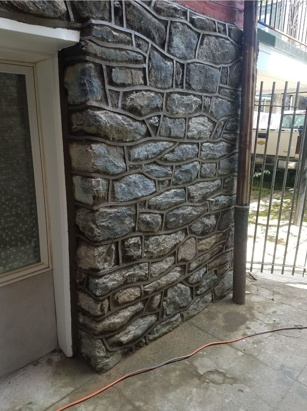 Man building a retaining wall with cinder blocks in an outdoor setting.