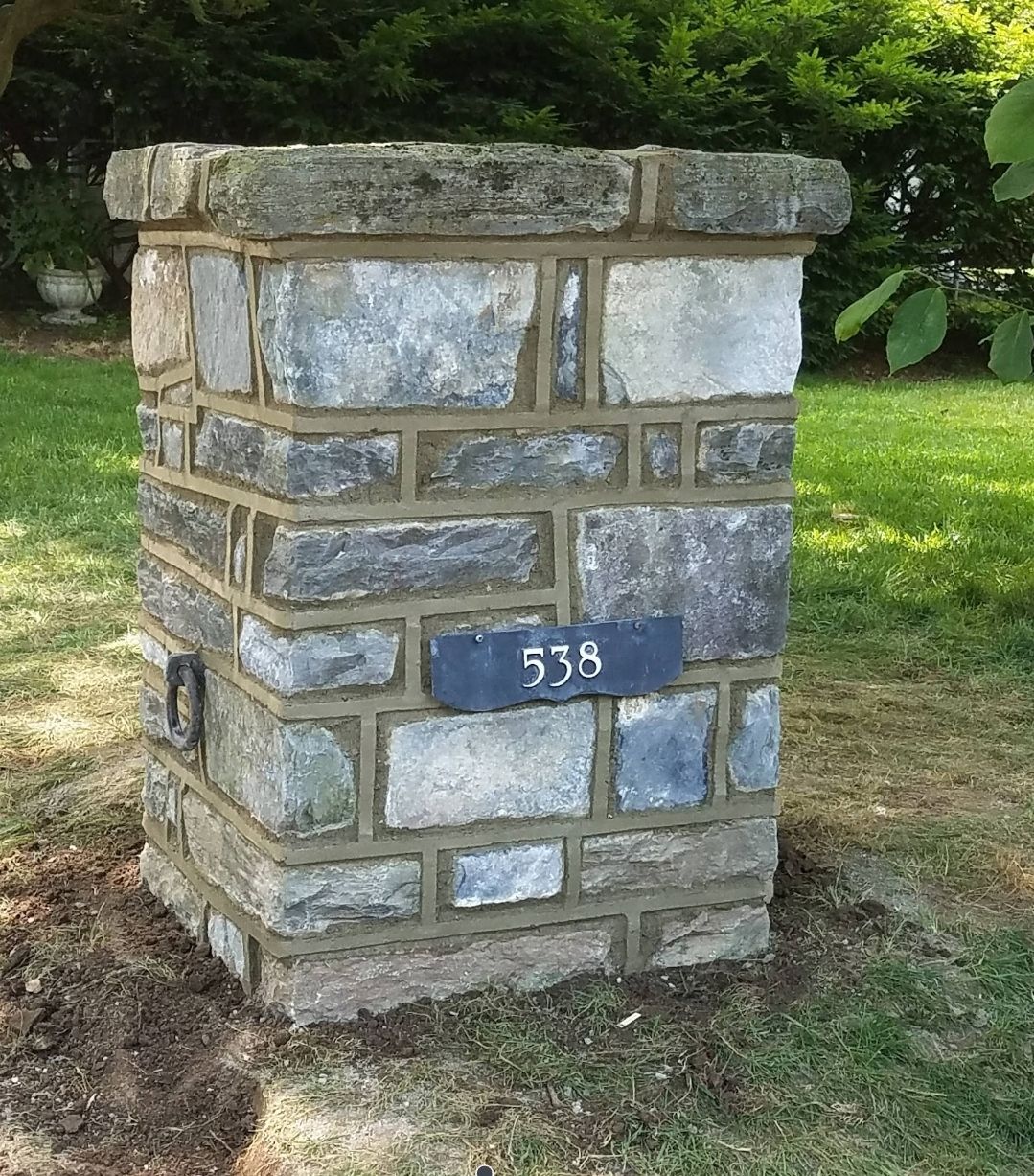 Close-up of a stone wall. Alternating rows of rectangular stones in shades of gray, beige, and orange.