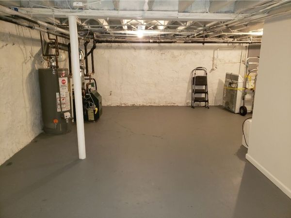 Man working on a newly paved walkway with stone edging beside a brick building.