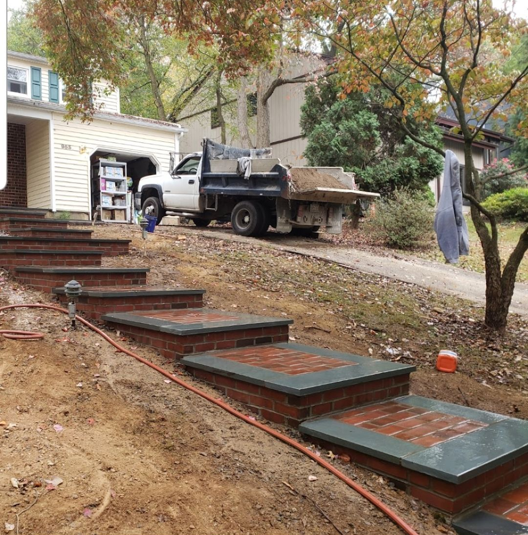 Brick steps leading up to a house with a truck parked on a gravel driveway.