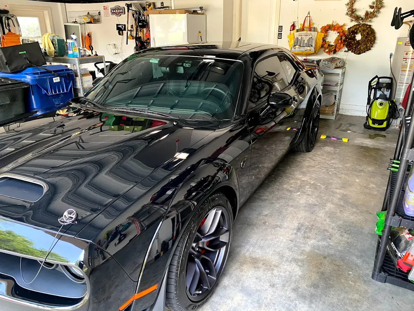 Black Dodge Challenger parked in a garage, reflecting the interior.