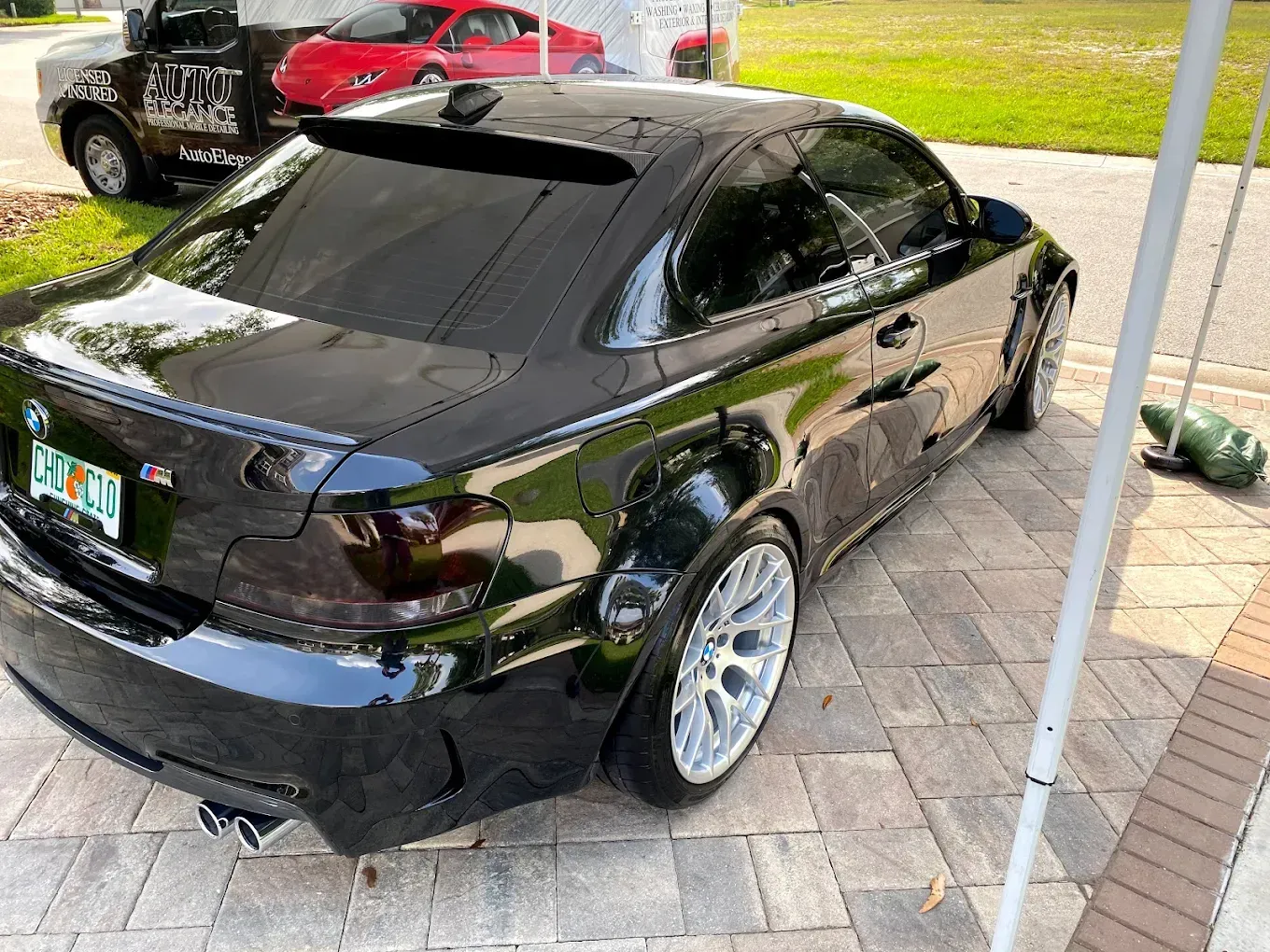 Black BMW coupe on a brick driveway, tinted windows, and silver rims.