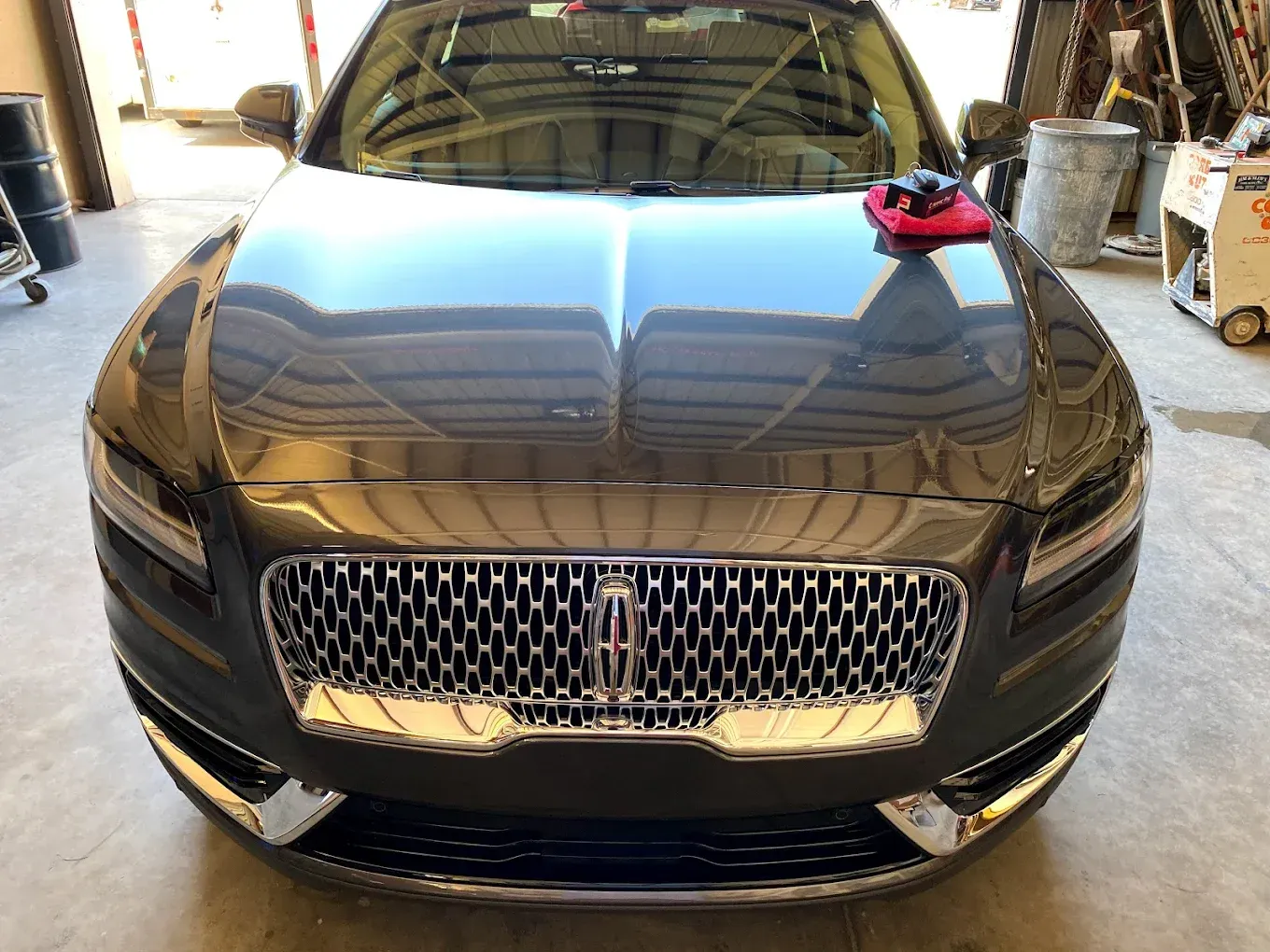 Dark gray Lincoln Continental car, shiny grill, red detailing cloth on hood.
