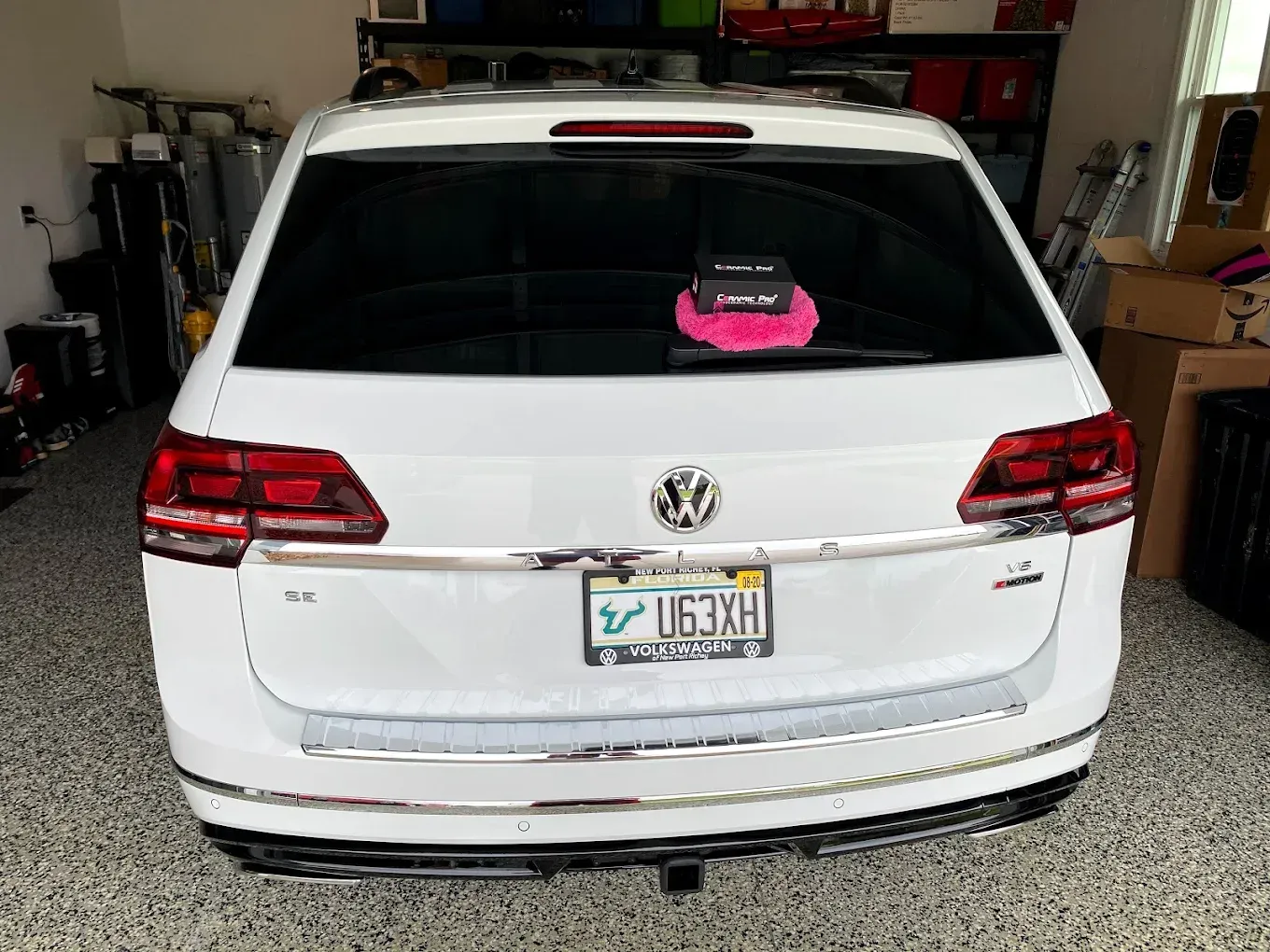 White Volkswagen SUV parked inside garage, with rear window covered and Florida license plate.