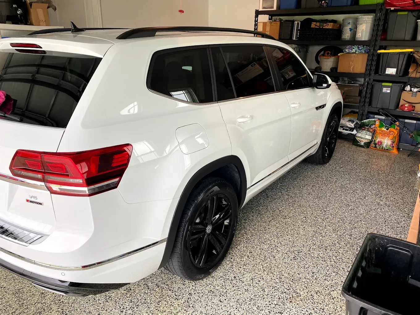 White SUV parked in a garage with black wheels and tinted windows.