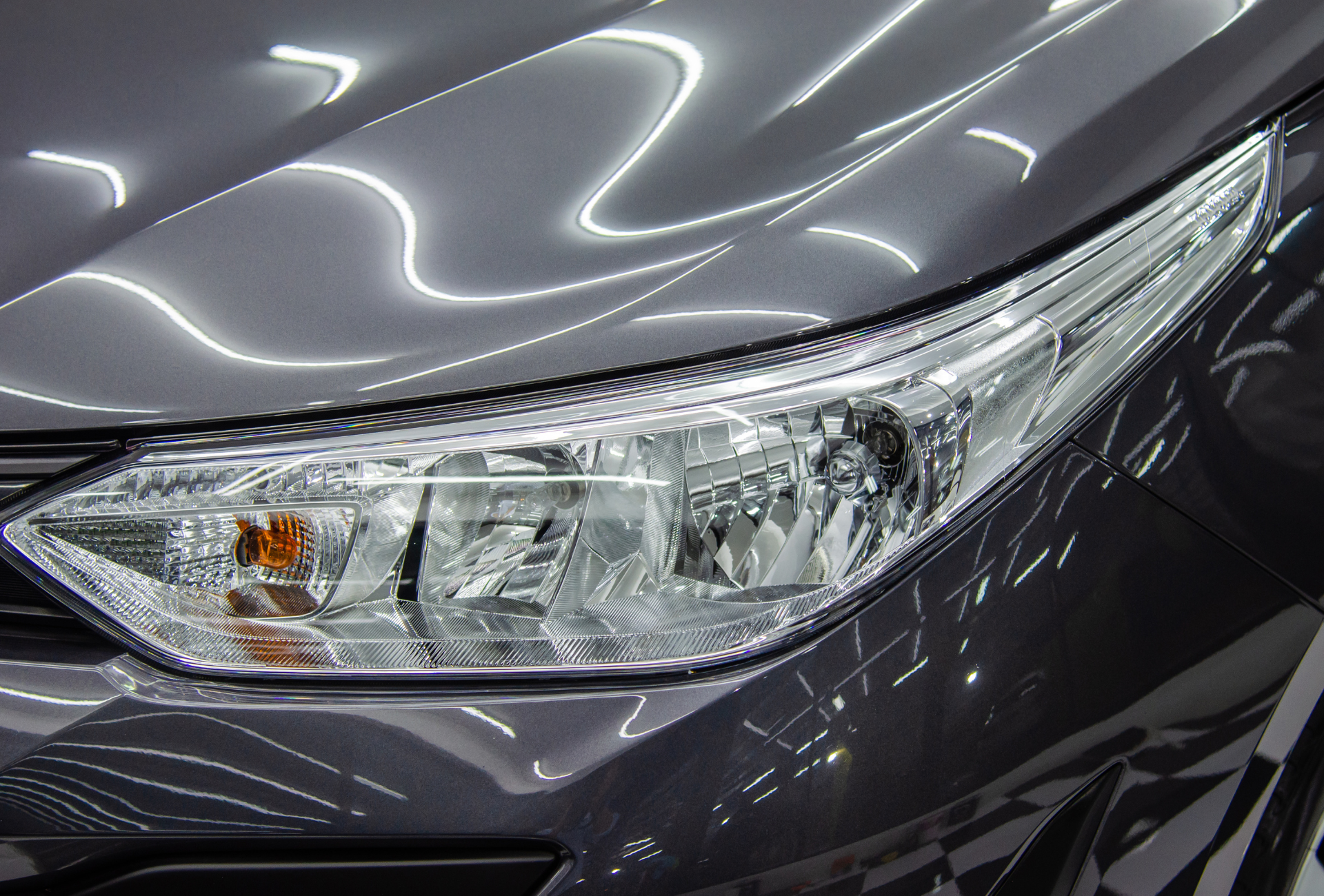 Close-up of a car headlight. Gray car body reflects light, headlight with bright lenses.