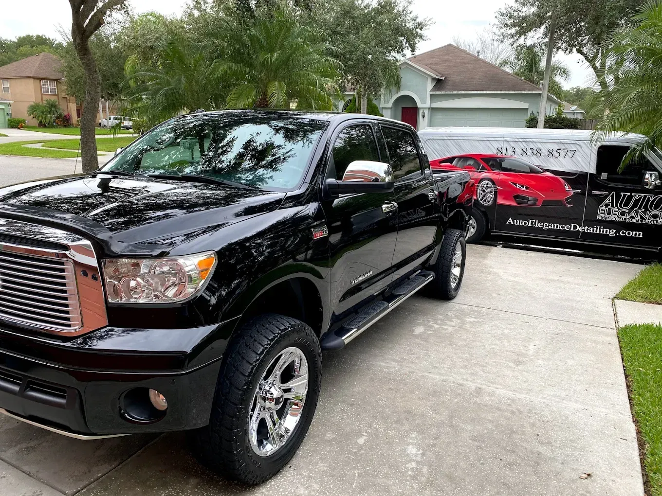 Black Toyota Tundra truck parked in a driveway with a car cover over another vehicle.