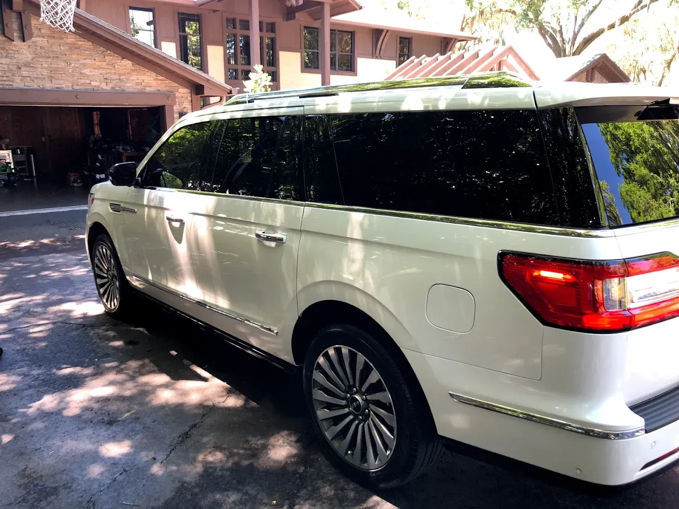 White Lincoln Navigator SUV parked in front of a house with tinted windows.