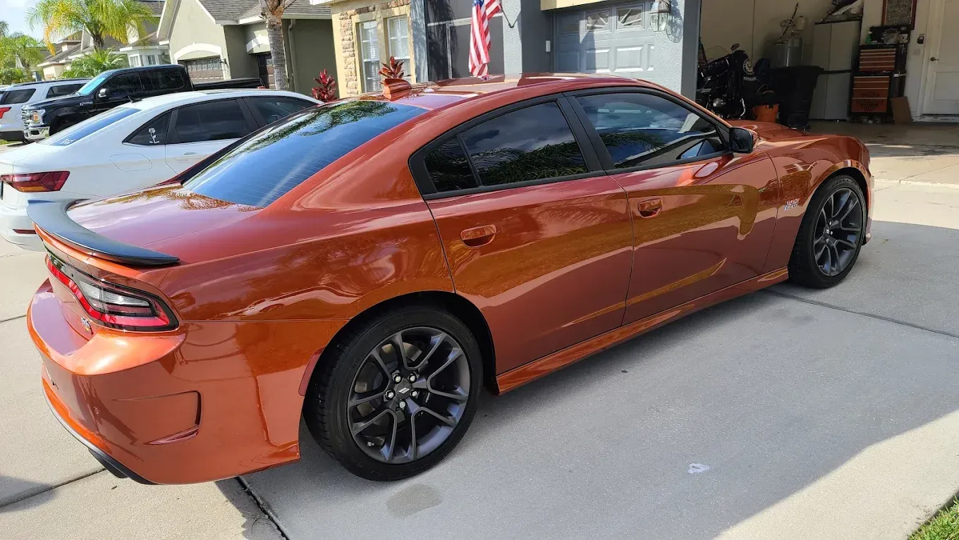 Orange Dodge Charger parked on a driveway.