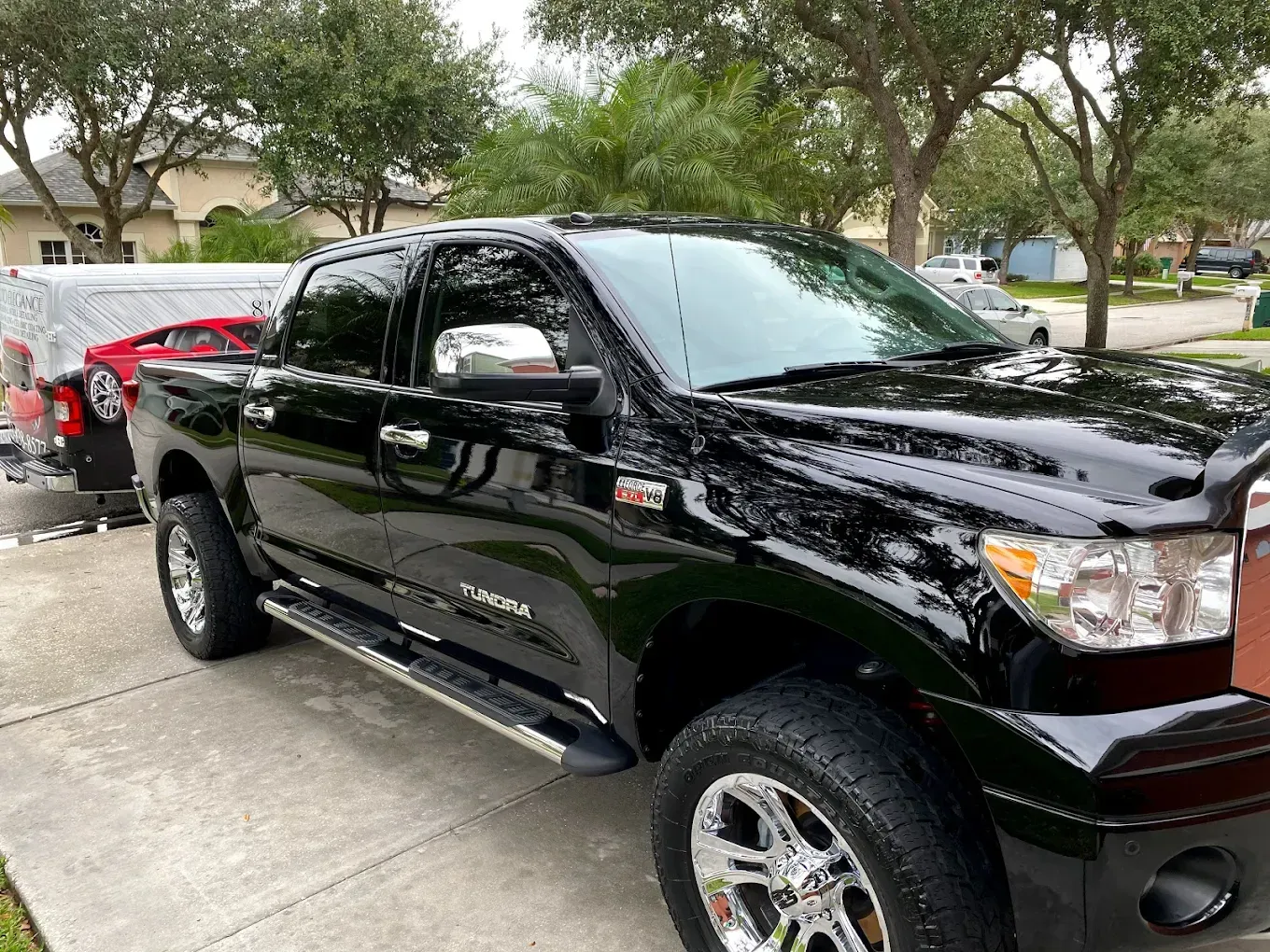 Black Toyota Tundra truck parked on a driveway, chrome wheels, sunny outdoor setting.