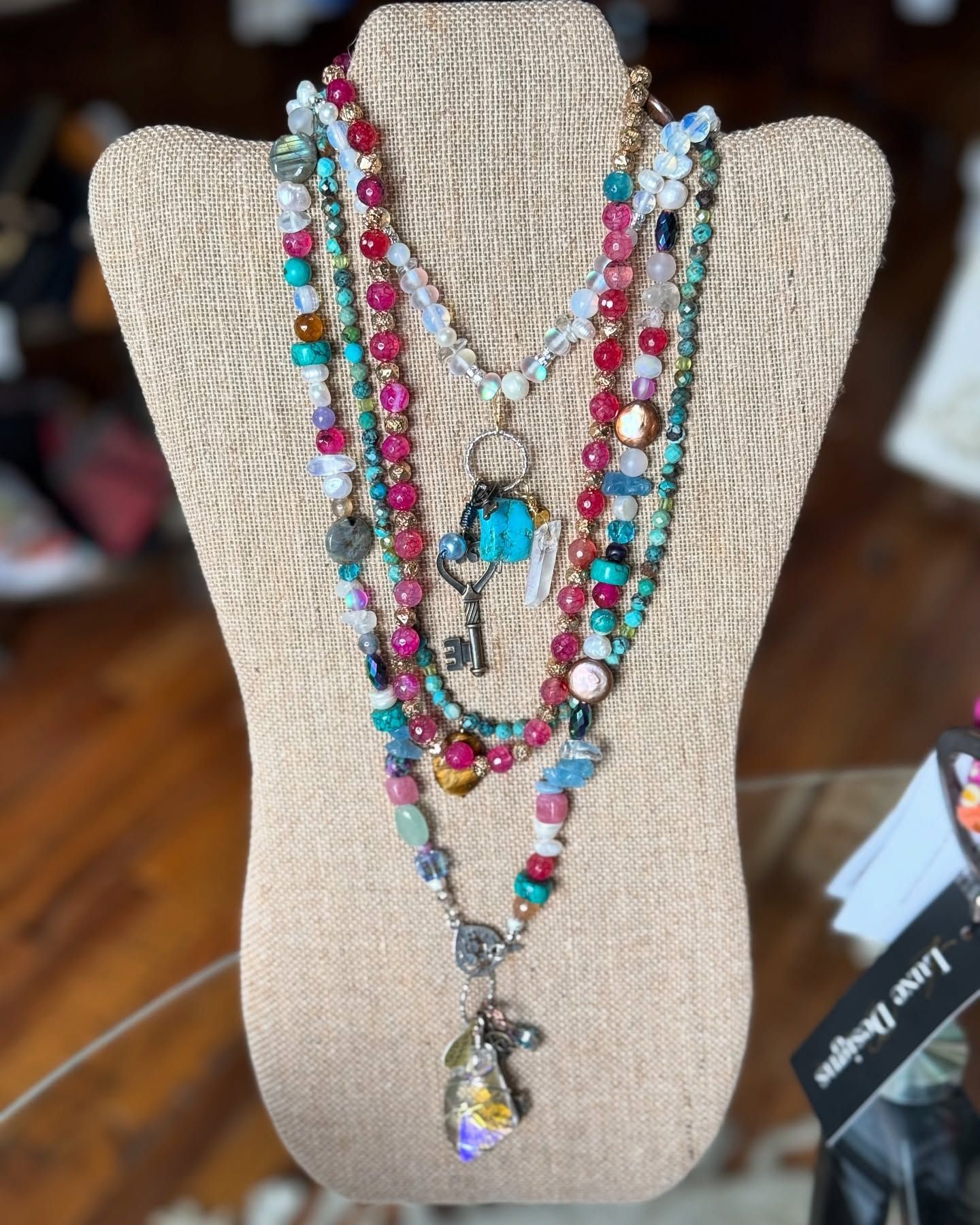 Necklaces on a mannequin; various colors of beads, layered; key pendant.